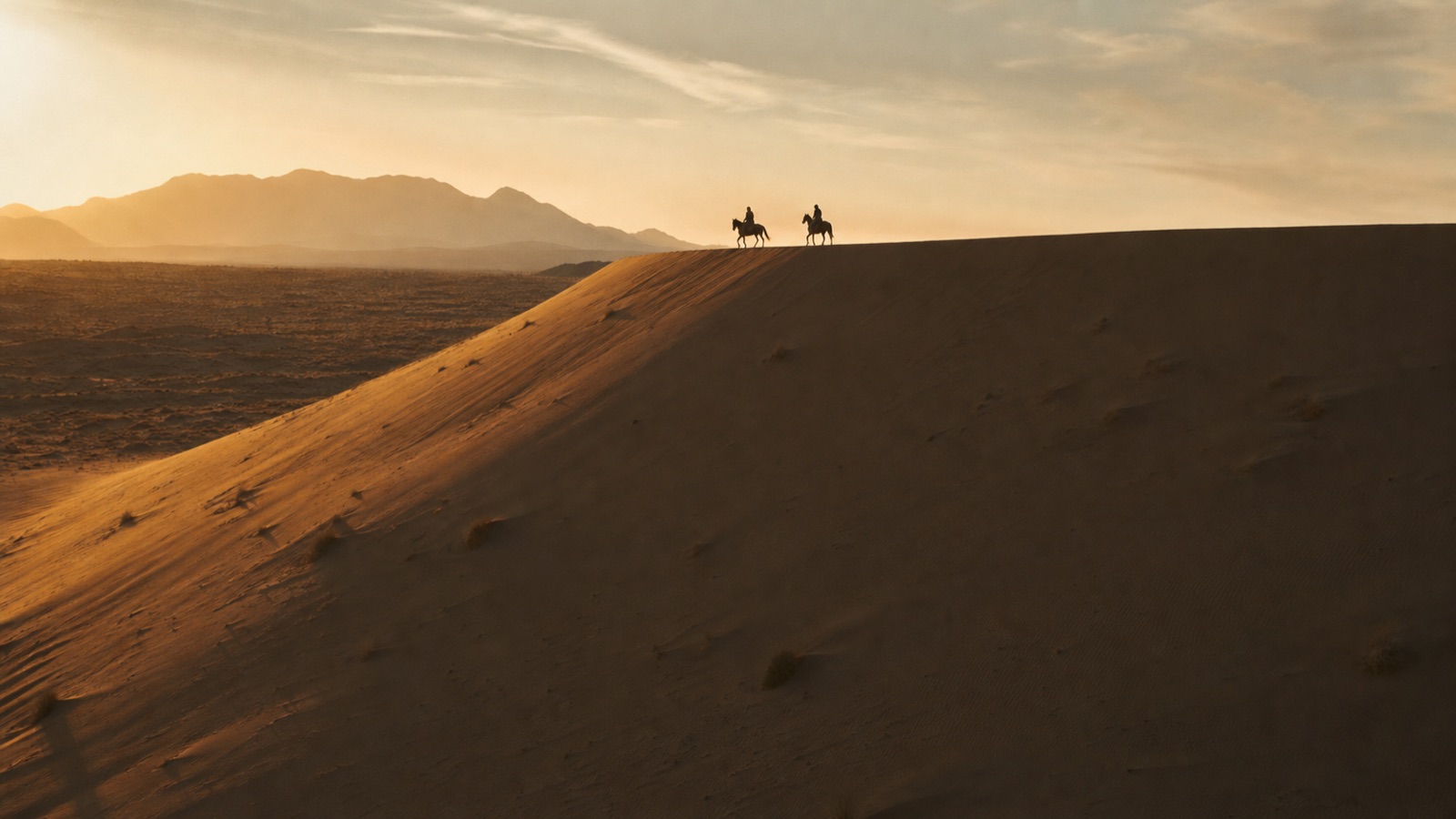 Riders crossing a desert ridge at golden hour